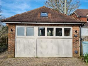 een garage met witte deuren en ramen op een bakstenen huis bij The Annexe at Albourne in Albourne