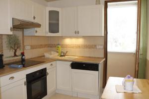 eine Küche mit weißen Schränken und einem schwarzen Geschirrspüler in der Unterkunft Gionova furnished flat in Aix-en-Provence