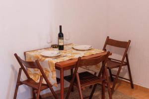 uma mesa com uma garrafa de vinho e duas cadeiras em Apartment Kjara em Tivat