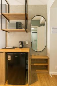 eine Küche mit einem schwarzen Kühlschrank und einem Spiegel in der Unterkunft BHomy Brooklin - Charmoso com varanda BUR108 in São Paulo