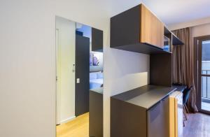 uma cozinha com armários pretos e uma cama num quarto em BHomy Brooklin - 300m estacão da Brooklin BUR101 em São Paulo