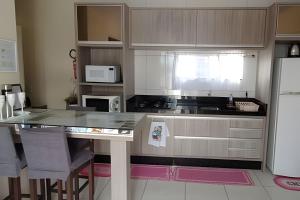 a kitchen with a counter and a refrigerator at Apto a 300m da praia, próx. Aeroporto, BetoCarrero in Navegantes