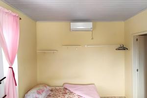 1 dormitorio con 1 cama con cortina rosa en Apto a 300m da praia, próx. Aeroporto, BetoCarrero, en Navegantes