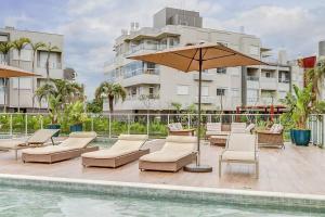 una piscina con tumbonas y sombrilla en BHomy Campeche Condomínio delicioso Spa club, en Florianópolis