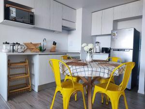 cocina con mesa y 4 sillas amarillas en Encantador depto 2D2B con estacionamiento vista al MAR ServicioHOM en Antofagasta