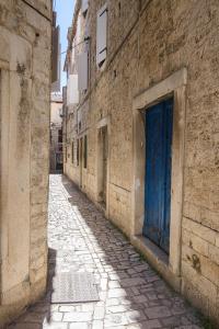 an alley with a blue door on the side of a building at Sobe Bartul Trogir in Trogir