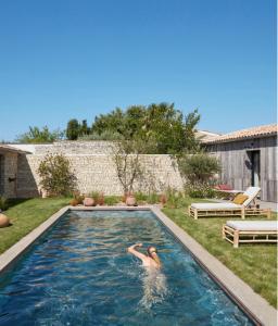 a woman swimming in a pool in a backyard at Maisons 322 - L'Insolite in Le Bois-Plage-en-Ré