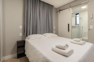 ein Schlafzimmer mit einem großen weißen Bett mit Handtüchern darauf in der Unterkunft BHomy Paulista - Novo e bem localizado MR44 in São Paulo