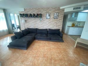 a black couch in a living room with a brick wall at Piso delante de la playa La Pineda con 2 habitaciones in La Pineda