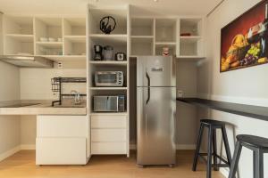 uma cozinha com um frigorífico e um balcão com bancos em BHomy Paulista - Perfeita localizacao MR173 em São Paulo
