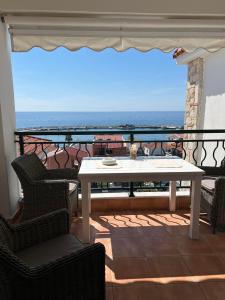 a white table and chairs on a balcony with the ocean at Skioni Soula Apartment in Nea Skioni