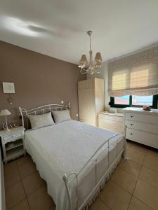 a bedroom with a white bed and a chandelier at Skioni Soula Apartment in Nea Skioni +5 photos