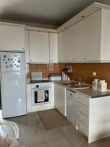 a kitchen with white appliances and white cabinets at Skioni Soula Apartment in Nea Skioni