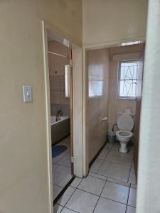 een badkamer met een toilet, een bad en een raam bij Stay Sunrise in Nelspruit