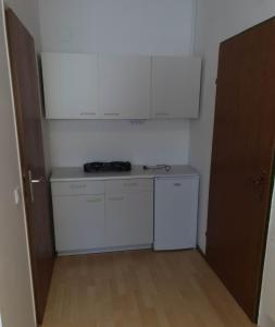 a small kitchen with white cabinets and a counter at Zimmervermietung Müller in Zeltweg