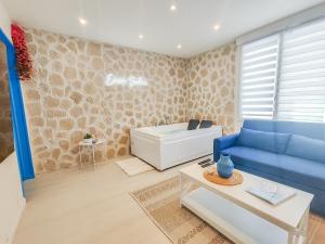 ein Wohnzimmer mit einem blauen Sofa und einer Badewanne in der Unterkunft Évasion Santorin - Jacuzzi & Relax in Le Havre