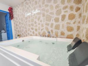 eine mit Wasser gefüllte Badewanne neben einer Steinmauer in der Unterkunft Évasion Santorin - Jacuzzi & Relax in Le Havre
