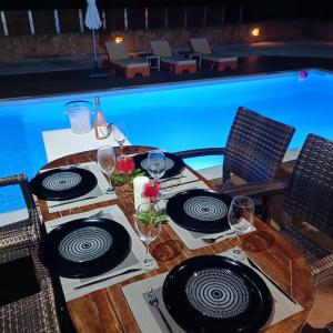Drosoula Villa 3bdr private swimming pool في Chorafakia: طاولة مع أطباق وكؤوس النبيذ بجوار حمام سباحة