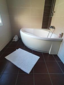 uma banheira branca na casa de banho com piso em azulejo em Chambres d'hôtes chez Manon em Sampans