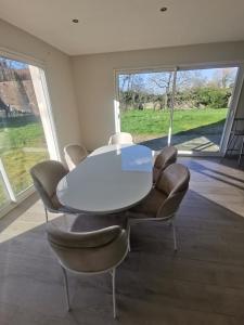 una sala da pranzo con tavolo e sedie bianchi di Chambres d'hôtes chez Manon a Sampans