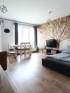 ein Wohnzimmer mit einem Bett, einem Tisch und einem TV in der Unterkunft Sweet Heart Home in Stettin