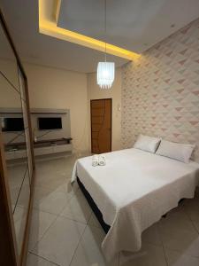 - une chambre avec un grand lit blanc et une télévision dans l'établissement Casa Confort, à Juazeiro do Norte