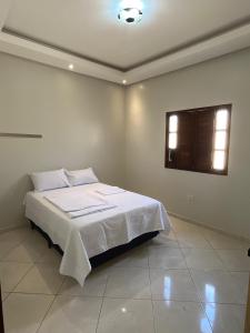ジュアゼイロ・ド・ノルテにあるCasa Confortのベッドルーム1室(白いシーツ付きのベッド1台、窓付)