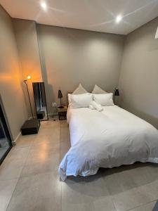 - une chambre dotée d'un grand lit avec des draps et des oreillers blancs dans l'établissement On Fredman Drive, à Johannesbourg