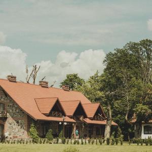 un edificio con tetto rosso su un campo di Poganty - Obora a Giżycko