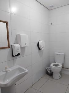 a white bathroom with a toilet and a sink at Aloha Hostel&CoWorking - Prox Aeroporto e Consulado in Porto Alegre