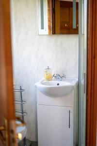 Glen Lodge في بوليماني: حمام مع حوض أبيض ومرآة