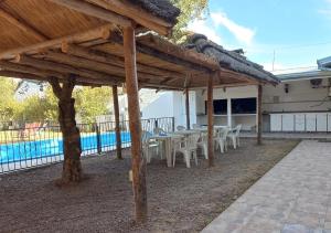 een houten paviljoen met tafels en stoelen naast een zwembad bij Colorina Complejo Residencial II in San Rafael