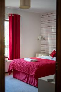 a bedroom with a red bed with a red curtain at Glen Lodge in Ballymoney