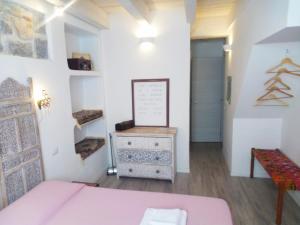 Habitación con cama rosa y vestidor. en B&B Terra - Stanza Viaggio, en Carloforte