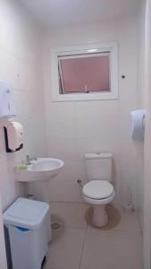 Baño blanco con aseo y lavamanos en Aloha Hostel&CoWorking - Prox Aeroporto e Consulado, en Porto Alegre