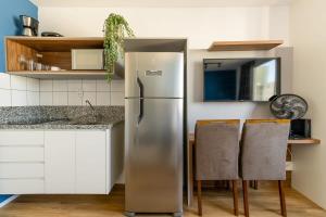 a stainless steel refrigerator in a kitchen with chairs at BHomy Brás - Studio prático bem localizado MV138A in Sao Paulo