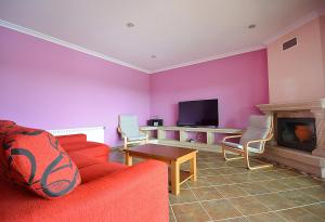 sala de estar con sofá rojo y TV en Villa con piscina en Cambados, en Cambados