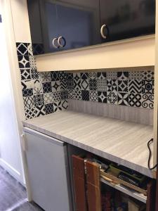 a kitchen with black and white tiles on the wall at Beau studio plein sud dans résidence tout confort in Le Dévoluy