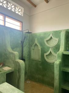 een badkamer met een groene muur met een wastafel en een raam bij Mgongo tree house in Jambiani