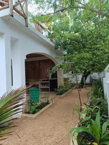 een wit gebouw met een boog in een tuin bij Mgongo tree house in Jambiani