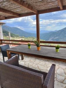 a wooden table and chairs on a patio with a view at Lousiou Nymphes escape suites in Dimitsana