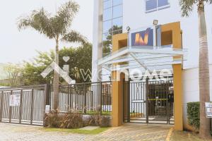 a gate in front of a building with palm trees at Aconchegante apartamento em Cotia in Cotia