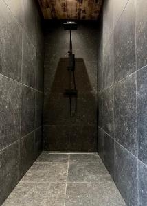 ein Bad mit einer Dusche in einer schwarzen Wand in der Unterkunft Chalet le Faye in Weismes