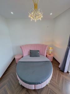 een slaapkamer met een roze bed en een kroonluchter bij Private 5Brs Pool Villa Luxurious Furniture in Da Nang