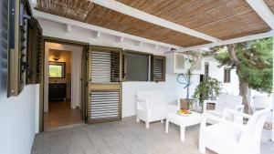 a patio with white chairs and a wooden ceiling at Hotel Rosamar - Emar Hotels in Es Pujols