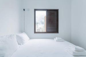 um quarto com uma cama branca e uma janela em BHomy Pompéia Muito bem localizado FI33 em São Paulo