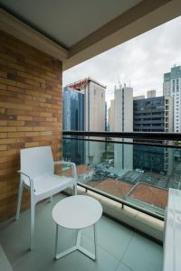 una silla blanca y una mesa en el balcón con vistas en BHomy Brooklin Ao lado do WTC e Berrini ET802, en São Paulo