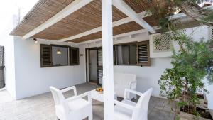 a patio with white chairs and a pergola at Hotel Rosamar - Emar Hotels in Es Pujols