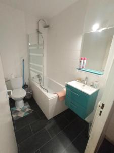 a bathroom with a tub and a toilet and a sink at Studio cosy à 10 minutes du centre-ville. in Saint-Étienne