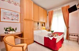 a bedroom with a bed with a table and a chair at Hotel Kennedy in Rimini